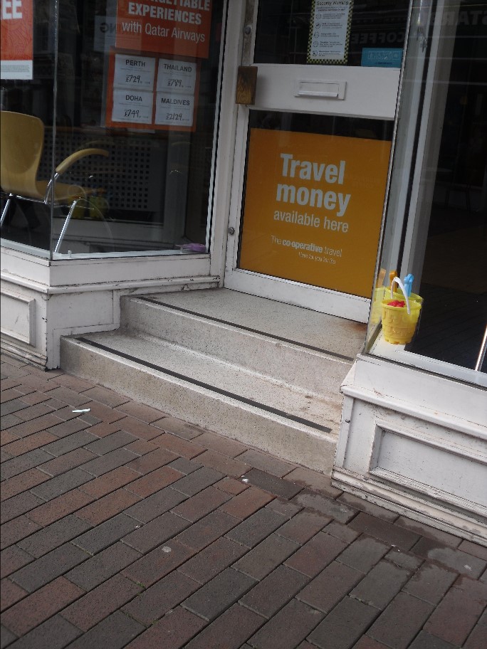 Steps make opening the door difficult for wheelchair users.